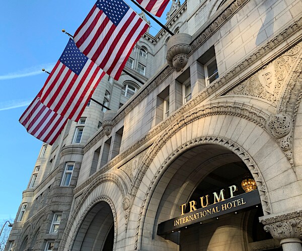 american flags wave about the signage for trump international hotel in washington, d.c.