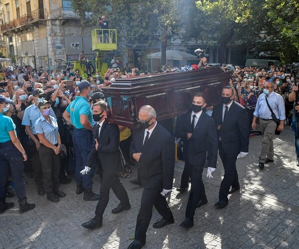 pallbearers carry coffin past hundreds of people