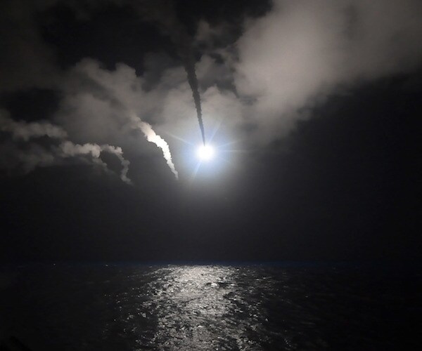 a missile is launched over the ocean lighting up a dark night sky and reflecting off the water