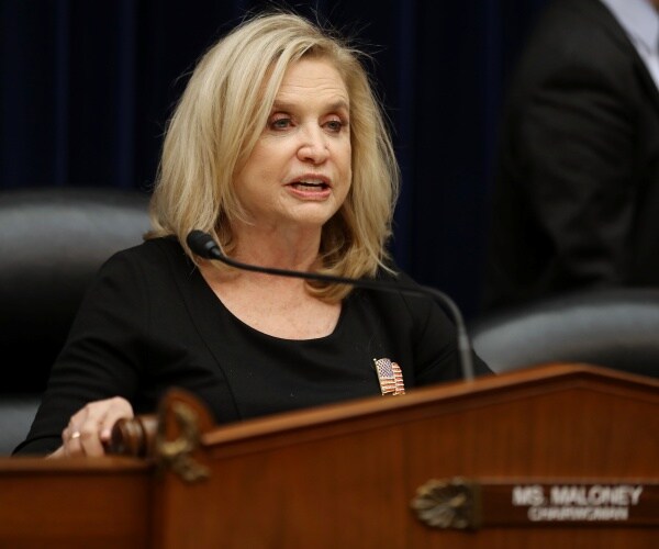 carolyn maloney in a black dress speaking at a podium