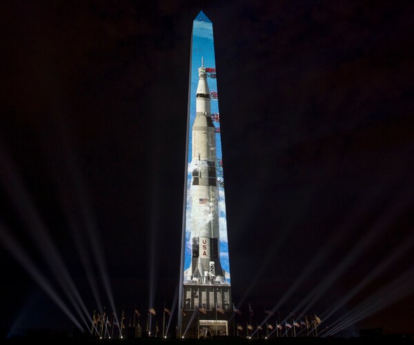 An image of the Saturn V rocket is projected onto the Washington Monument