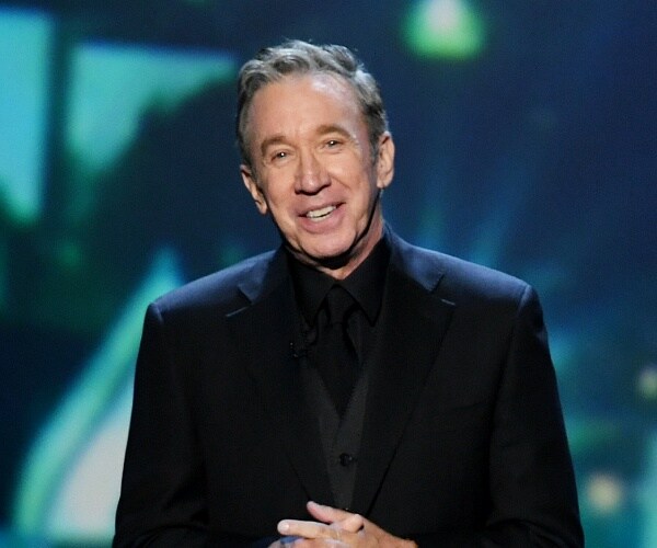 tim allen stands onstage with hands clasped
