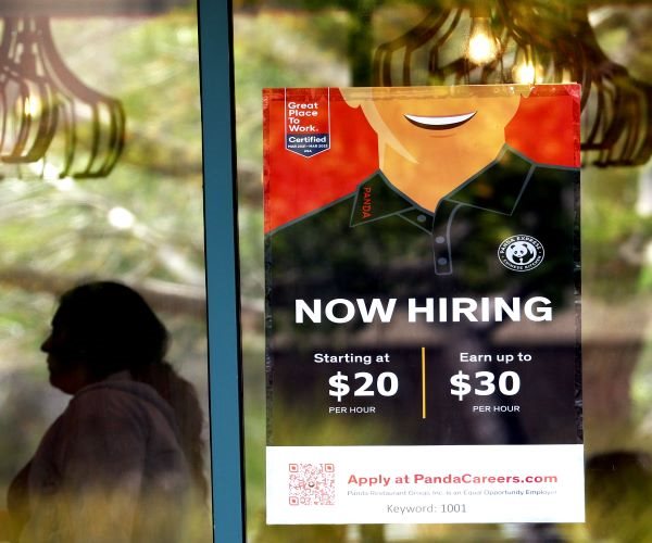 "Now Hiring" sign hanging in a window