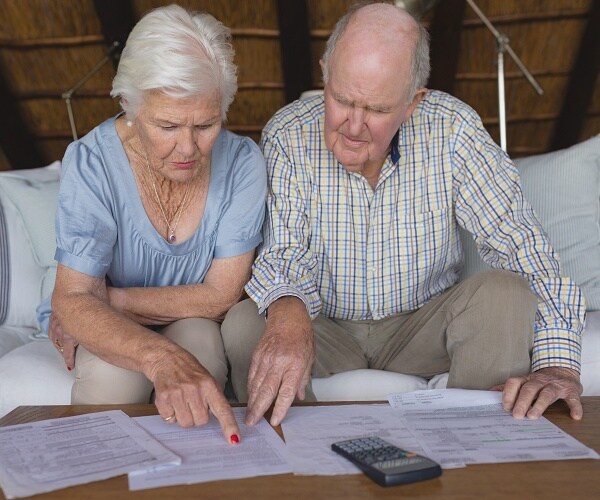 older couple look at bills on table
