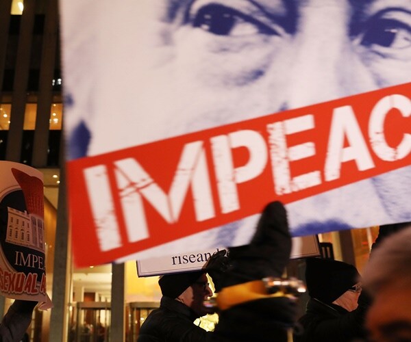 a protester holds a sign to impeach the president