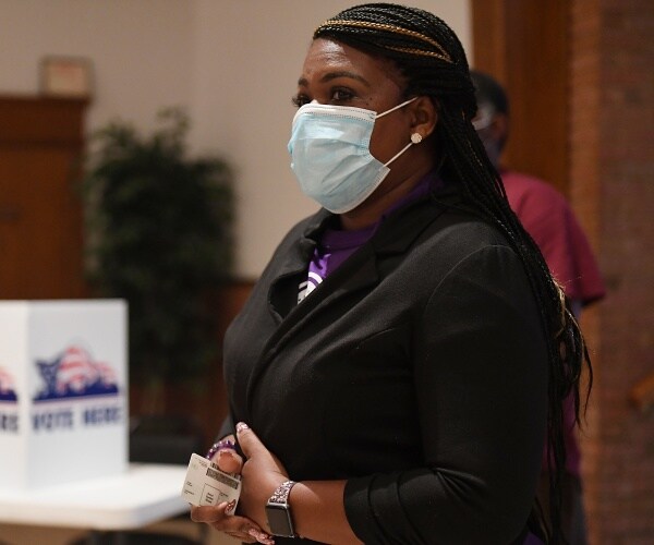 bush in a black sweater and purple shirt wearing a face mask