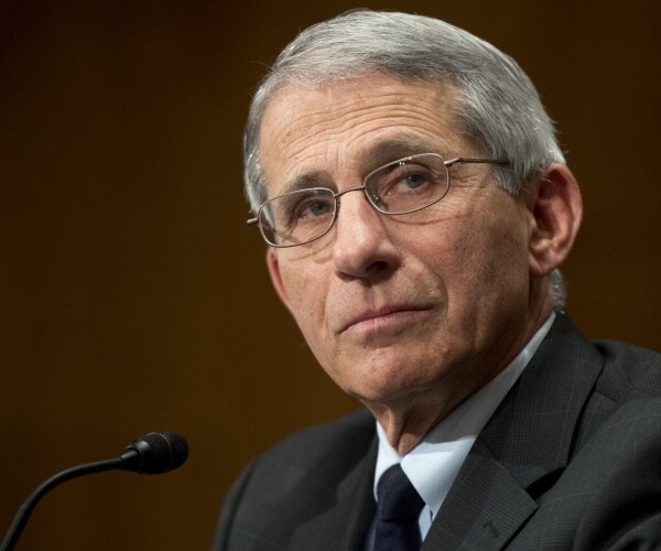 fauci in a dark gray suit with brown background