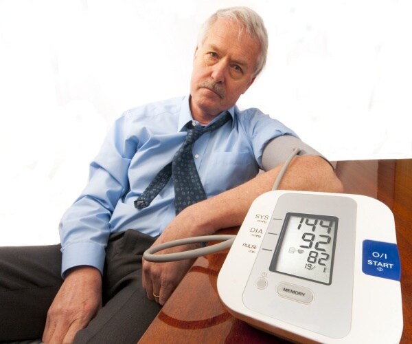 man looks worried as he gets his blood pressure taken and monitor shows it is high