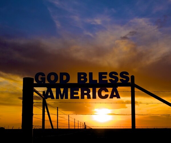 dramatic sunset with sign that reads god bless america