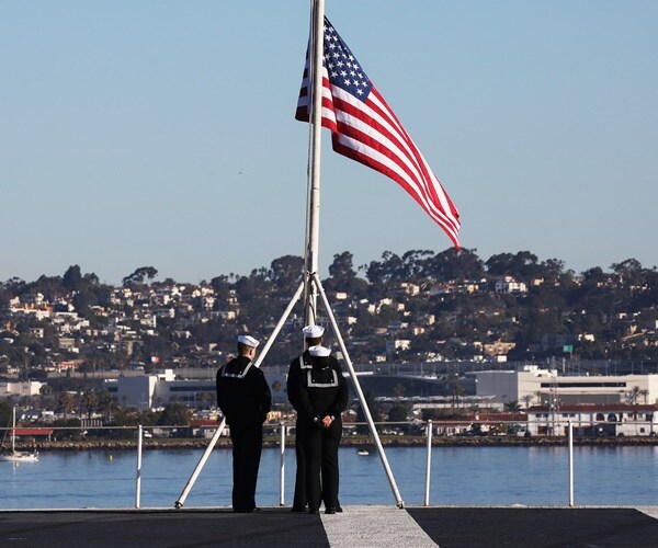 sailors take down the flag on the stern of the uss nimitz
