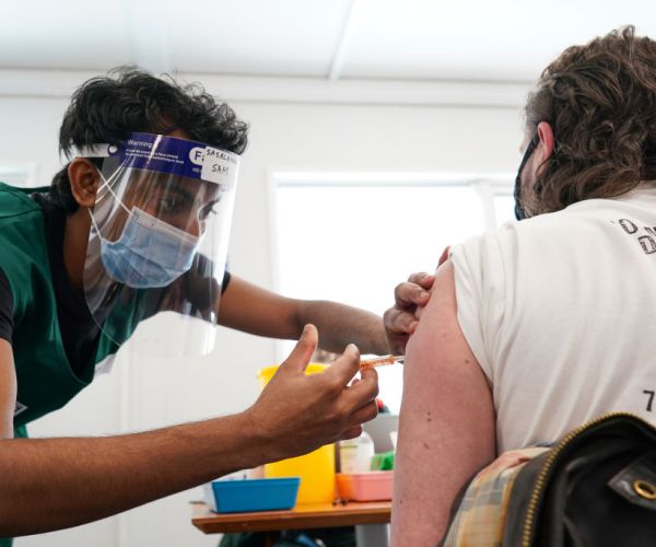 a nurse delivers a vaccination into the left arm of a patient
