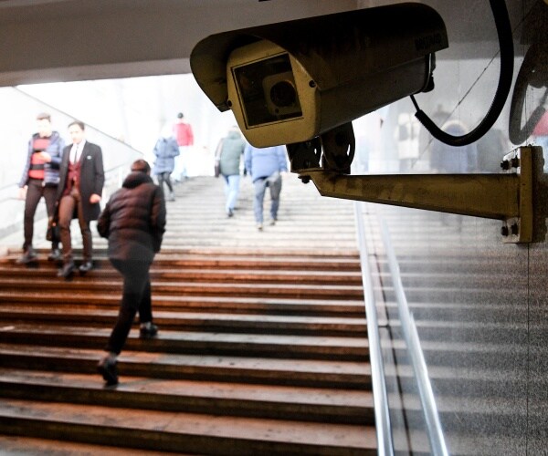 surveillance camera is shown with people walking up and down steps behind it