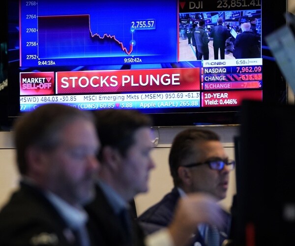 tv screen displays "stocks plunge" headline as traders work on computers in the nyse