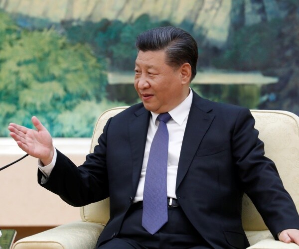 xi in a suit and purple tie sitting down