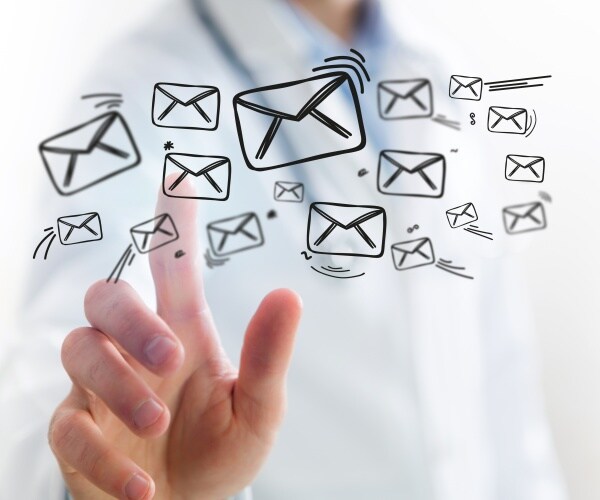 doctor touching a screen that has illustrations of envelopes to signify email