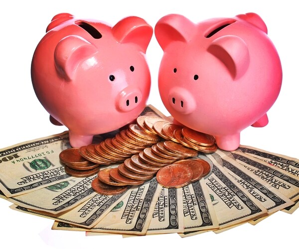 two pink piggy banks atop bed of ten $100 US currency dollar bills and pennies