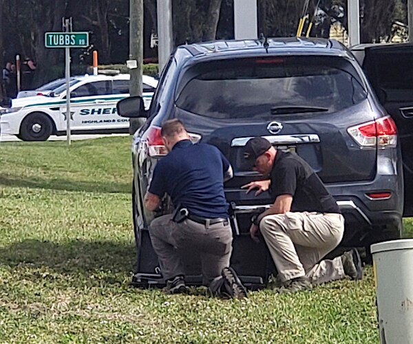 police officers take cover behind a black nissan rogue outside a florida bank during a hostage situation