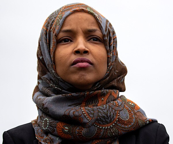 democratic representative ilhan omar stands quietly with a headdress on