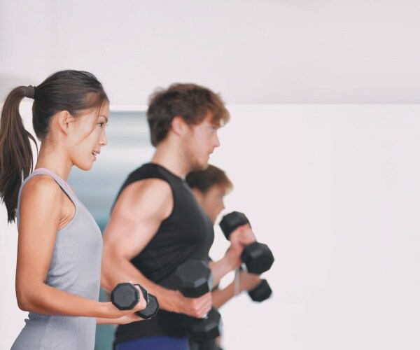 people in fitness class lifting weights