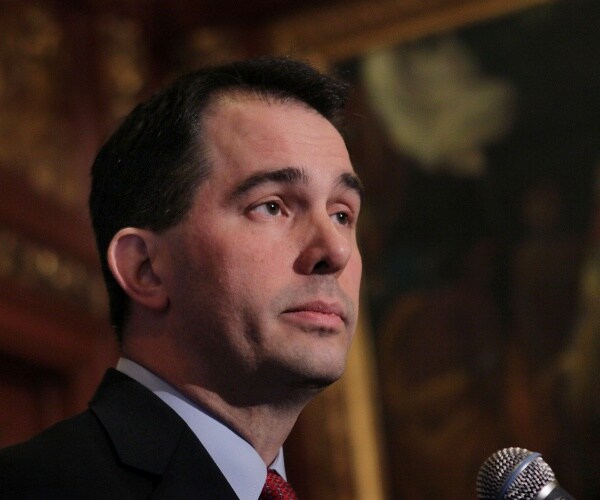 walker in a suit and red tie speaking into a mic