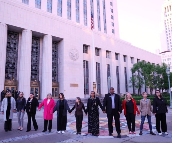 A group holds hands outside a landmark trial over whether social media platforms deliberately addict and harm children. 