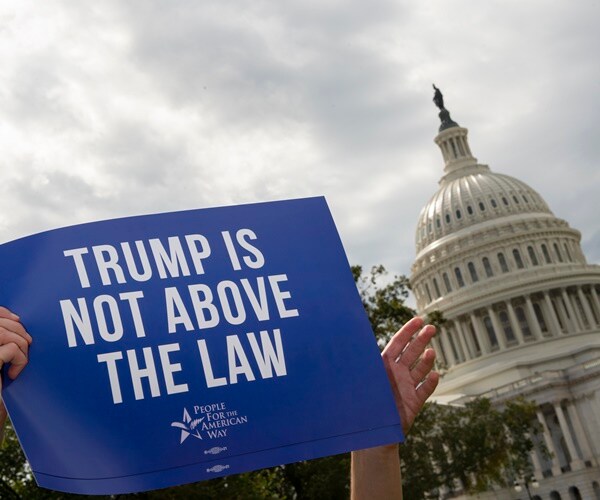 a protester holds up a sign, trump is not above the law