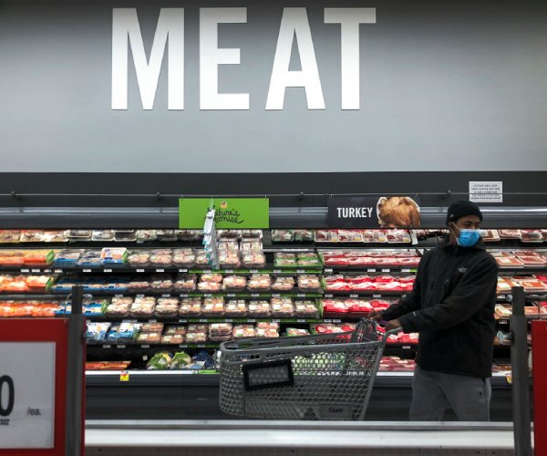 a shopper looks for items in the meat section at a grocery store