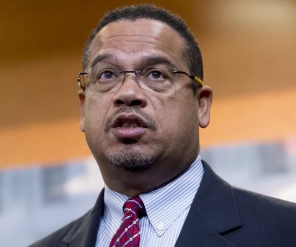 ellison in a suit and red and white patterned tie