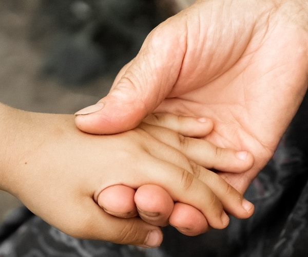 child and adults holding hands