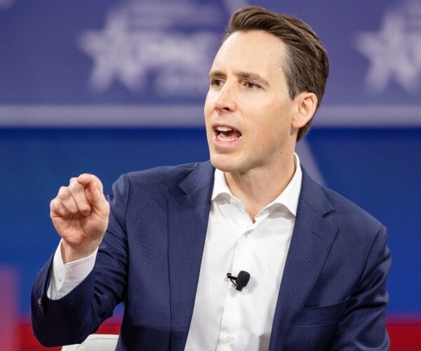 hawley in a blue suit and white shirt speaking at cpac