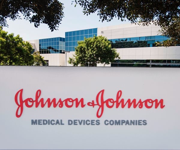 red script johnson & johnson logo displayed on sign in foreground of glass-clad office building