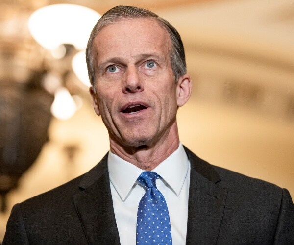 thune in a black suit and blue polka dotted tie