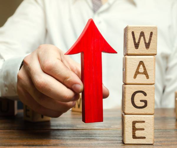man holds a red arrow pointing up next to blocks reading wage