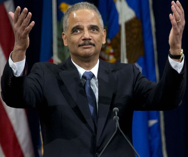 eric holder raises both hands in the air with his palms up