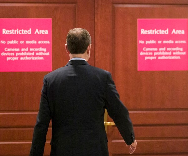 adam schiff walks to doors with restricted access signs on them