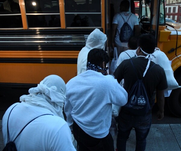 migrants being deported to guatemala wearing white board a school bus