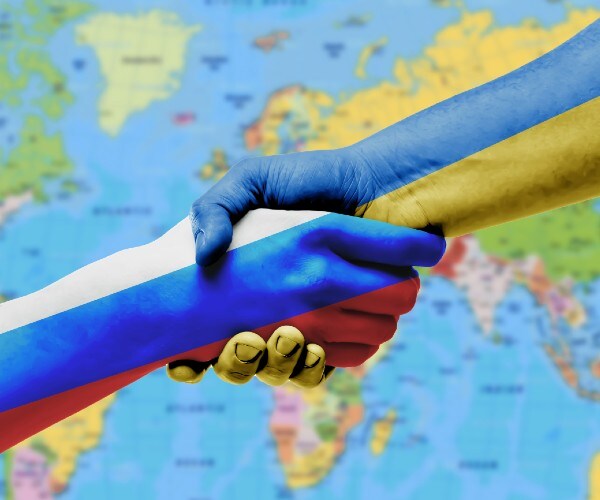 hands shaking that are painted like the russian and ukrainian flags