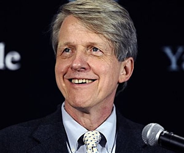 robert shiller speaking in front of yale banner background