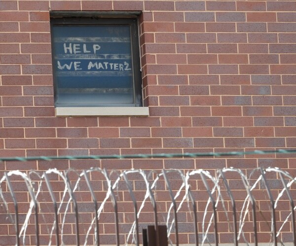 brick wall with window showing the words "help we matter 2"