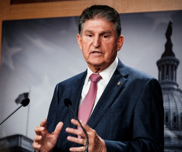 Sen. Joe Manchin speaks into a microphone at a press conference.
