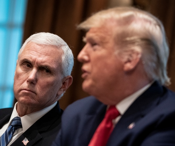trump looks at trump speaking in a suit and red tie 