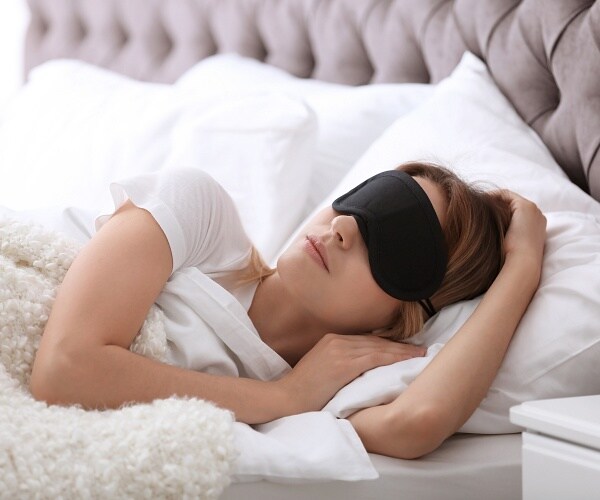 woman sleeping in bed wearing eye mask