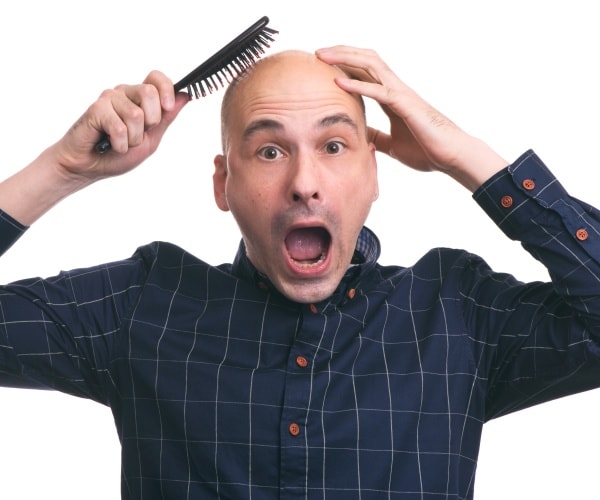 bald man with a hairbrush and shocked face