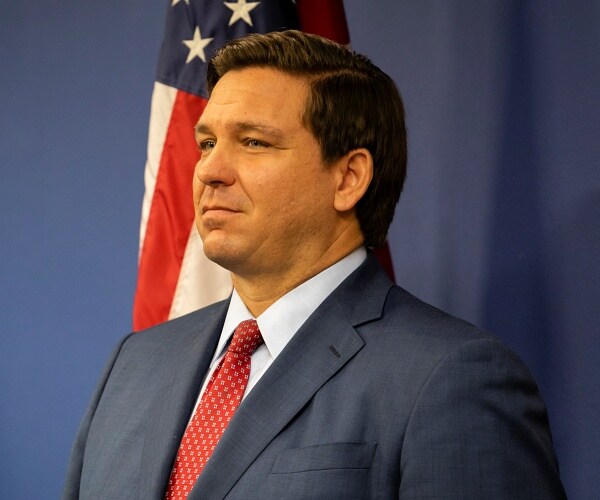 ron desantis stands in front of american flag