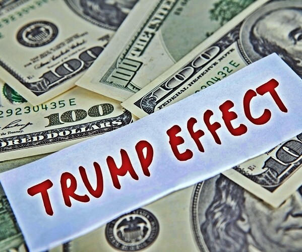 image of a pile of dollars currency and trump effect written in red capital letters 


