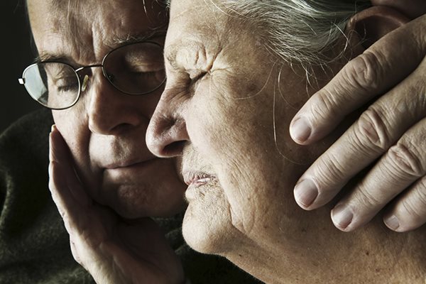 an older woman who looks upset is comforted by another person