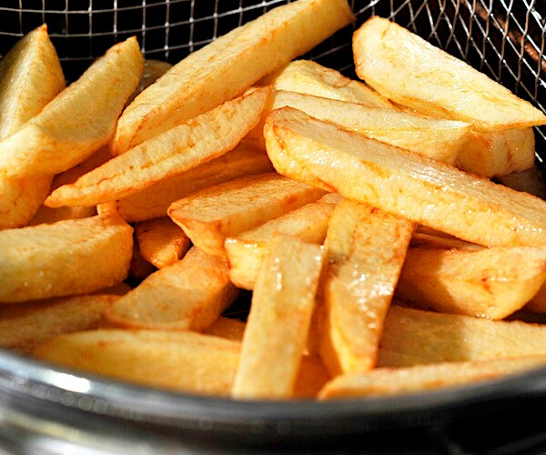 a bowl of greasy steak fries sit in a colander