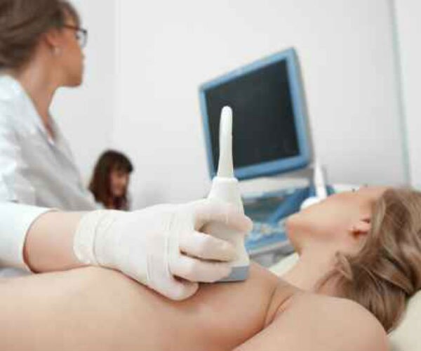 a doctor is examing a patient's breast as she lies back on  a table