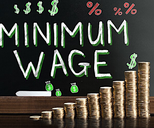 an illustration of stacks of gold coins with the words minimum wage behind it