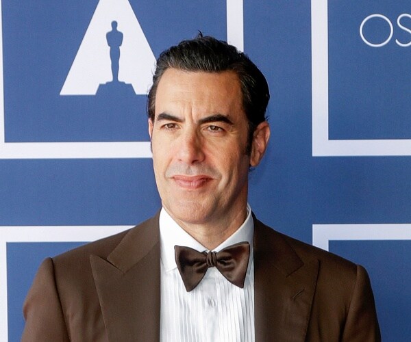 sacha baron cohen stands on red carpet